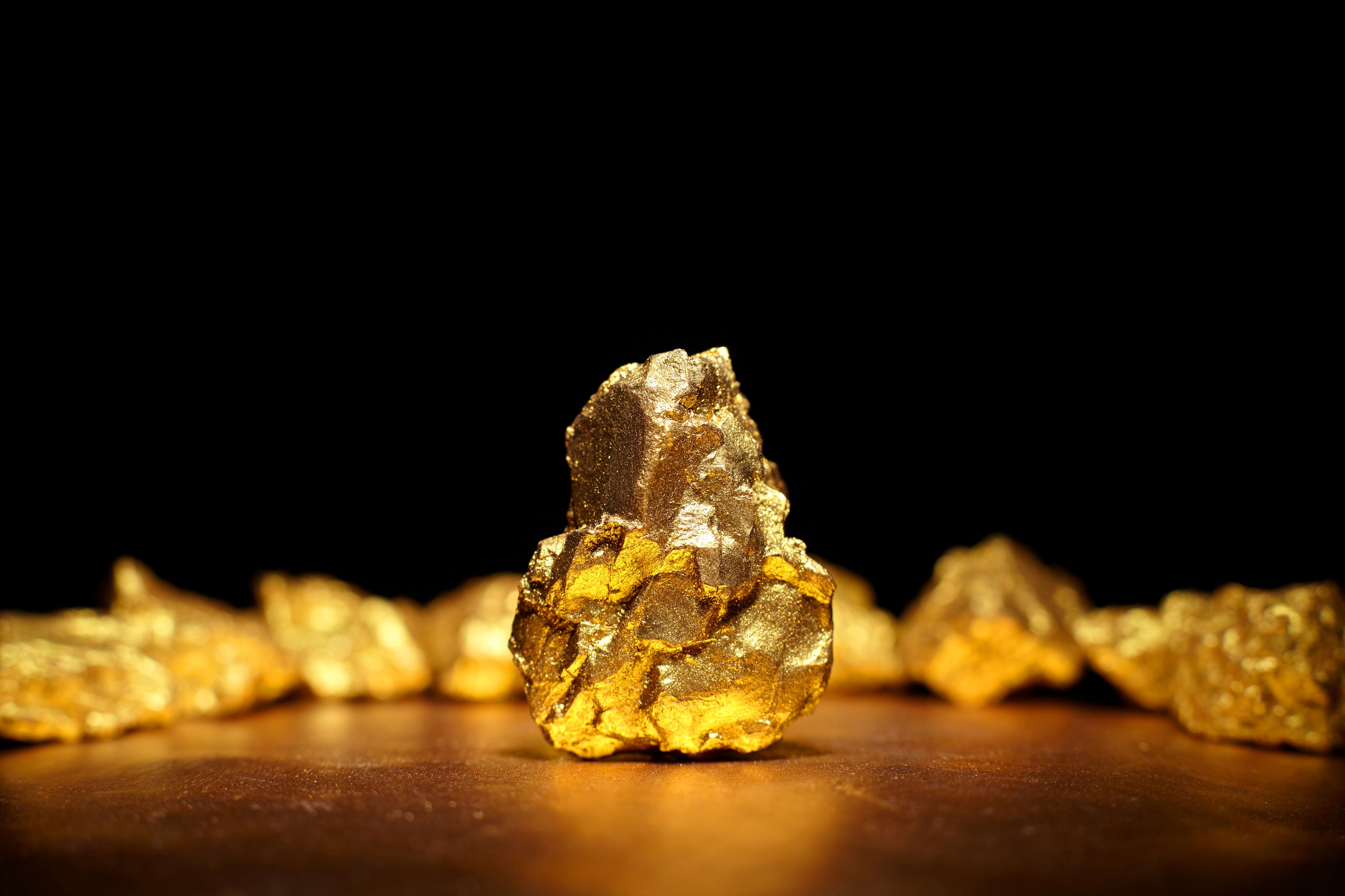 Nugget of gold shining brightly with other nuggets in background