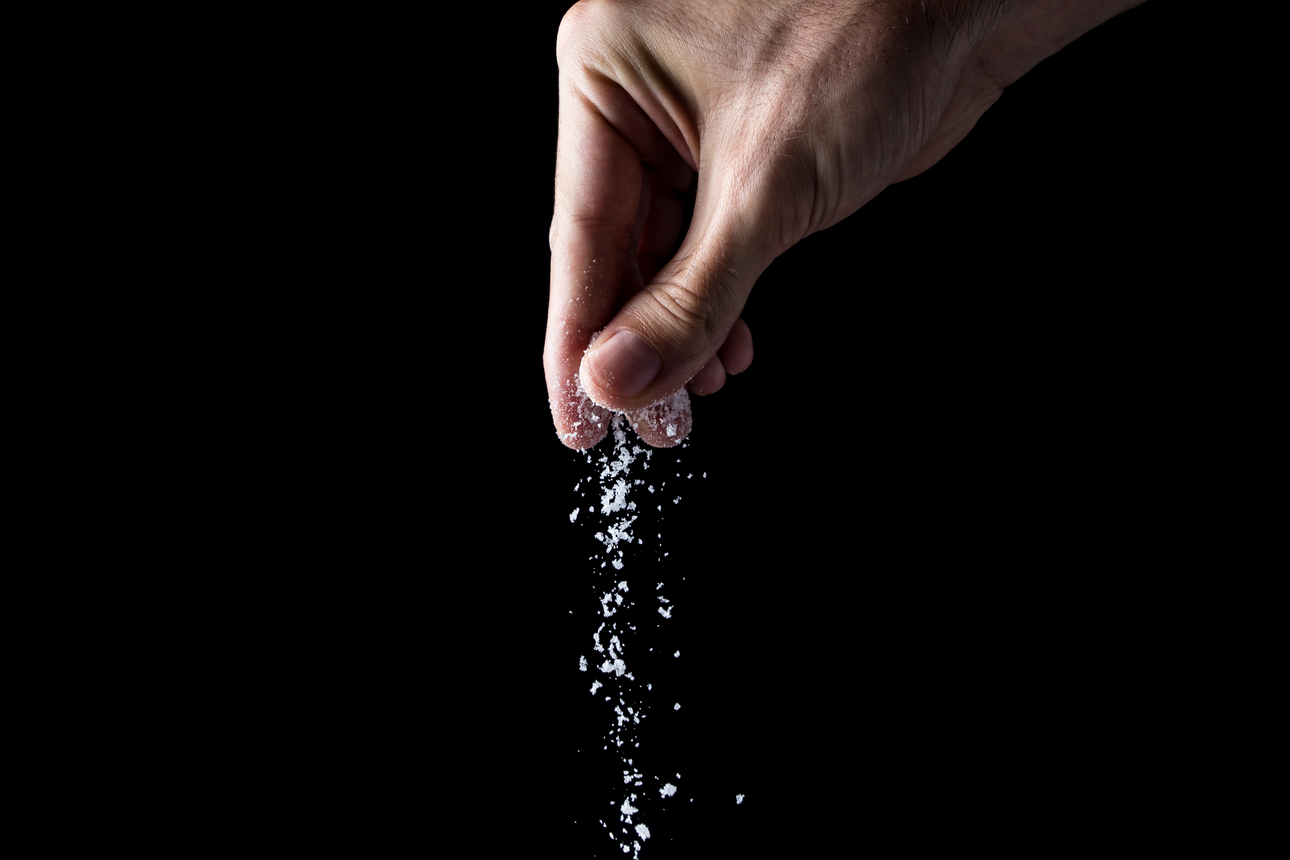 Salt being sprinkled against a black background