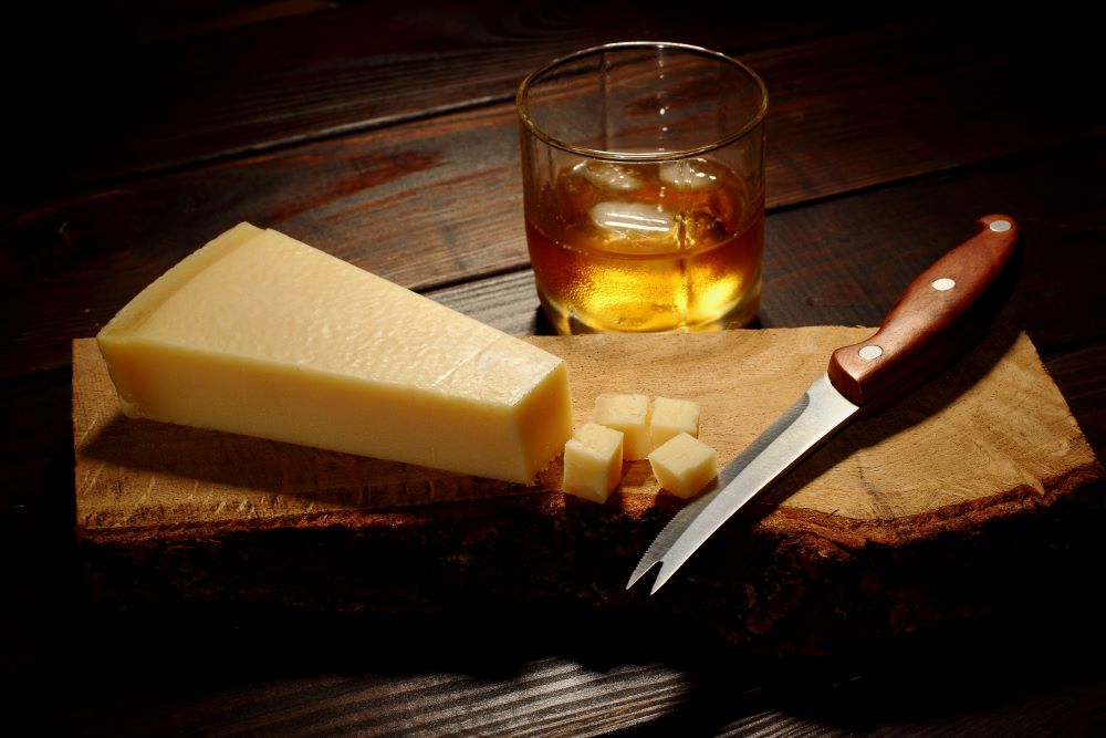 Cheese on a platter with a knife and whisky